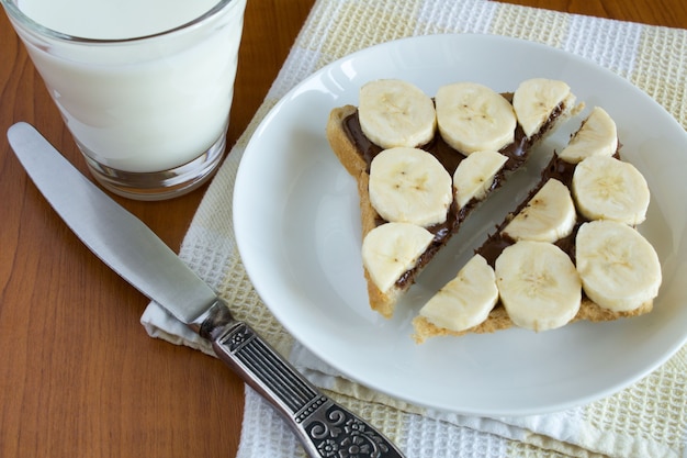 白い皿にチョコレートクリームとバナナでスライスしたトースト