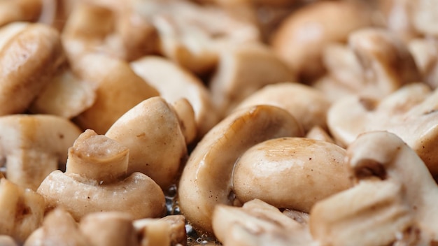 Sliced toasted champignon closeup Mushrooms are fried in oil in a pan background