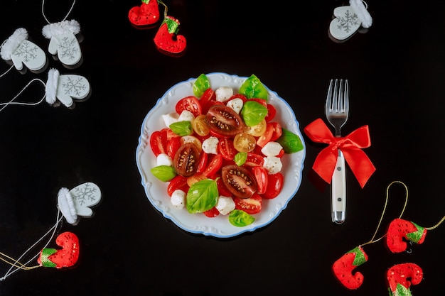 Sliced tomato and mozzarella salad with fork for Christmas dinner Vegetarian dish