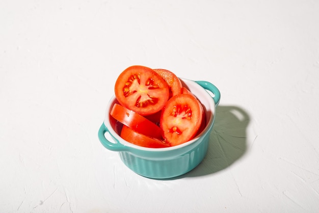 Sliced tomatoes in a cup on a white background