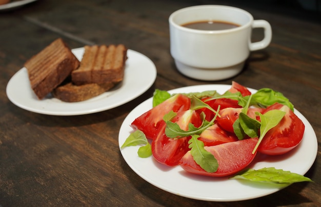 写真 トーストと一杯のコーヒーと白い皿にサラダとスライスしたトマト