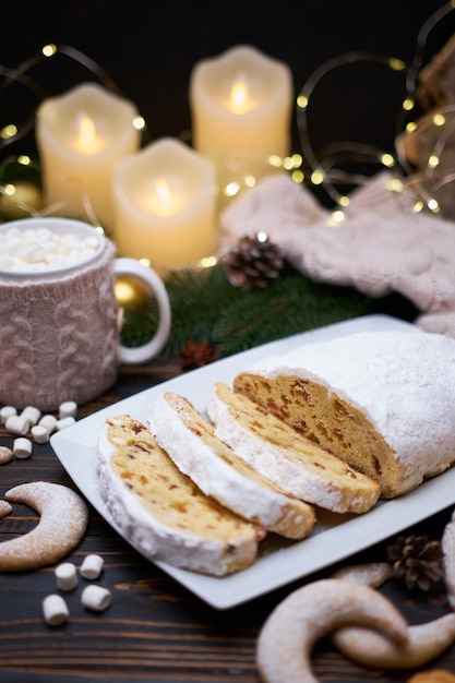 Sliced traditional christmas stollen cake with marzipan and new year decorations on wooden background