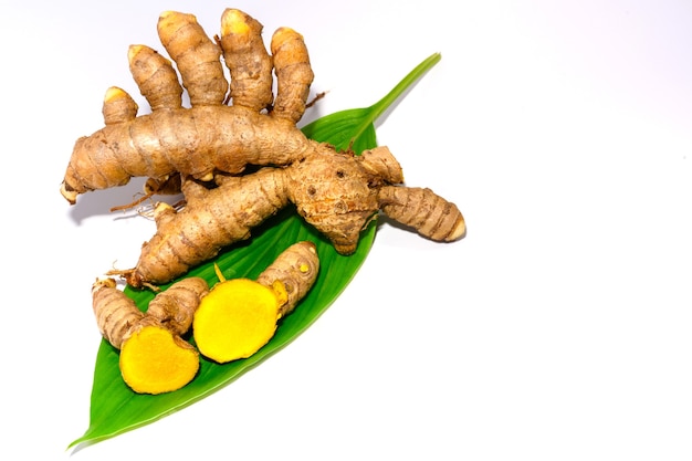 Sliced turmeric leaves and turmeric root isolated on white background close-up