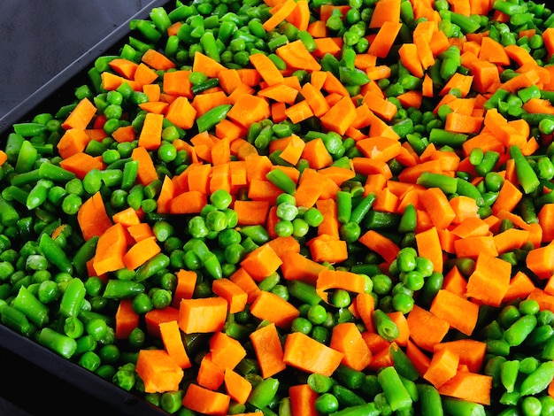 Photo sliced vegetables before baking on the pan for baking. carrots, green peas, green beans.