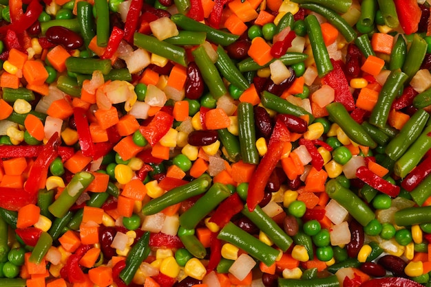 Sliced vegetables, corn, beans, peas, carrots, sweet peppers background.