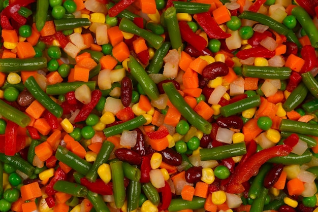 Sliced vegetables, corn, beans, peas, carrots, sweet peppers background.