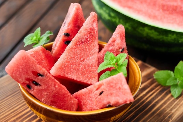 Sliced watermelon decorated with mint leaves on brown wooden background