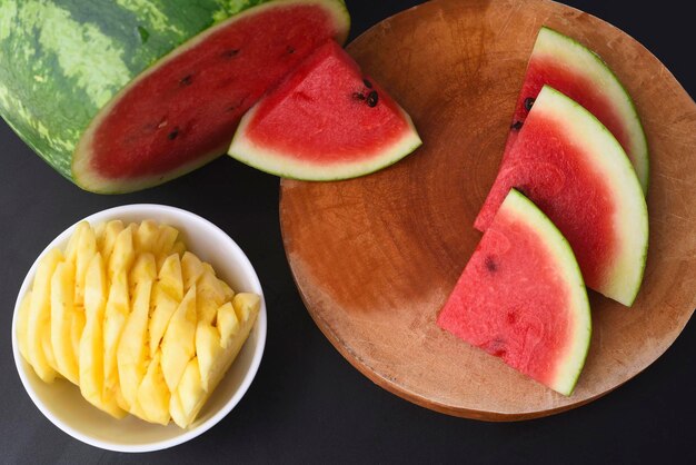 Sliced watermelon and pineapple on black background