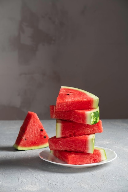 Sliced watermelon in a plate on a gray background