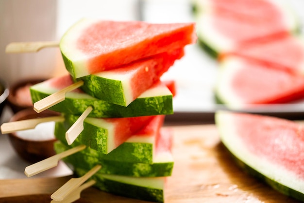 Photo sliced watermelon in triangle shapes on wooden sticks.