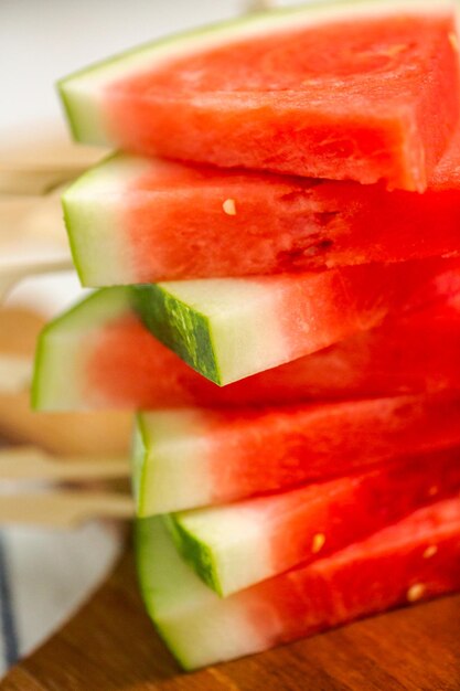 Sliced watermelon in triangle shapes on wooden sticks.