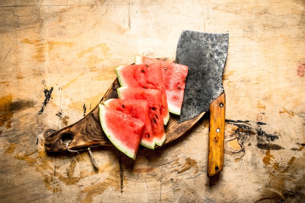 Sliced watermelon with an axe. On wooden background.