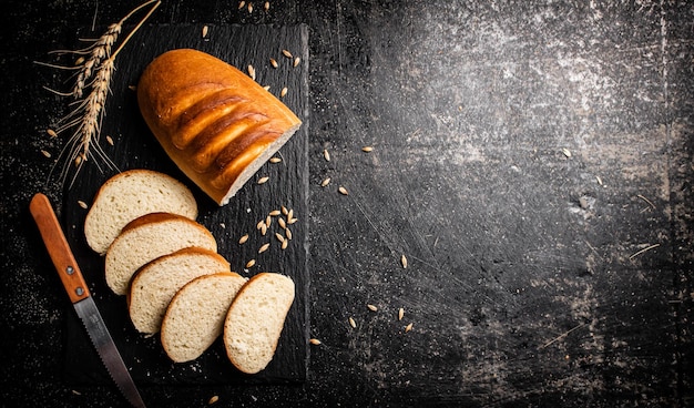 Нарезанный пшеничный хлеб ножом на каменной доске