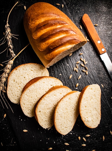 Sliced wheat bread with a knife on a stone board