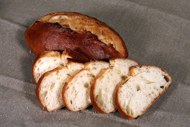 Sliced white bread lying in straw on grey linen tablecloth