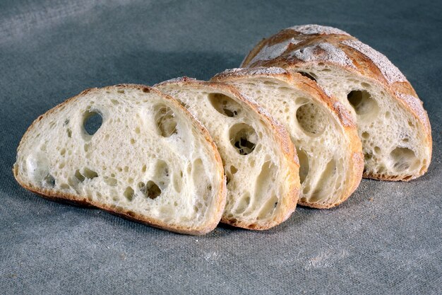 Нарезанный белый хлеб, лежащий на скатерти в сером белье