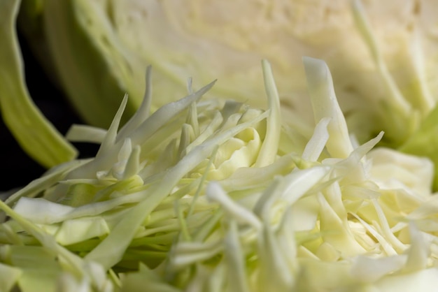 Нарезанная белокочанная капуста на столе. Приготовление салата из свежей белокочанной капусты.