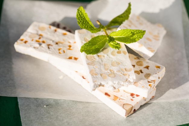 Sliced white nougat with almonds on wooden table