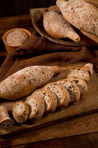 Sliced whole grain bread, baguettes on rustic wood with whole
flour pot in the background.