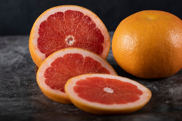 Sliced and whole grapefruit on concrete