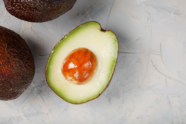 Sliced and whole organic Hass avocado on a gray surface