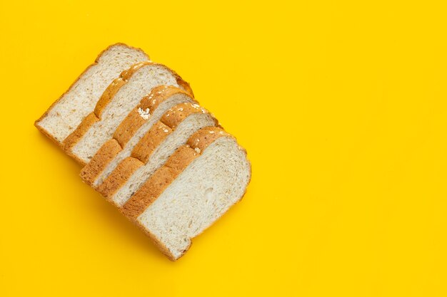 Sliced whole wheat bread on white surface.