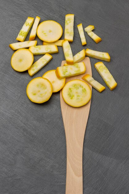 Sliced yellow zucchini in a spoon and on the table