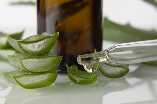 Slices Aloe Vera leaves and pipette on light background close up