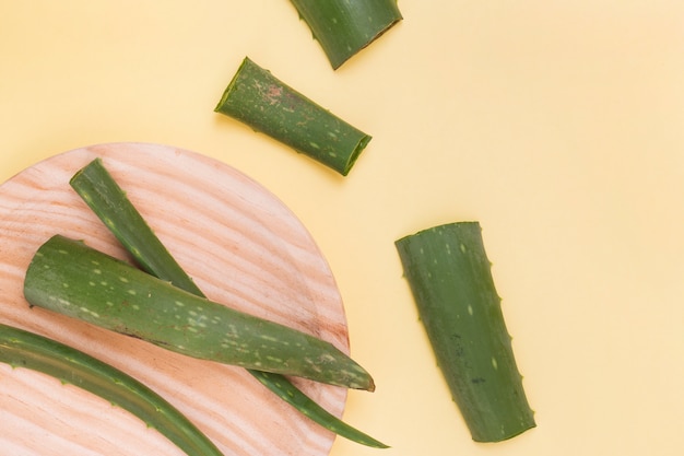 Photo slices of aloe vera leaves on wooden plate over the yellow background