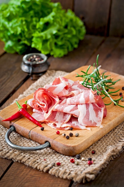 Photo slices of bacon on the wooden background