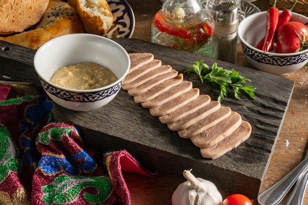 Slices of boiled beef tongue with horseradish and coriander, sliced and served on a wooden chopping board