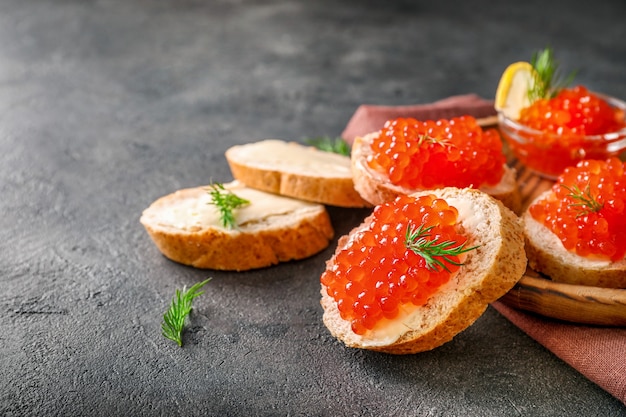 Photo slices of bread with red caviar on dark background.