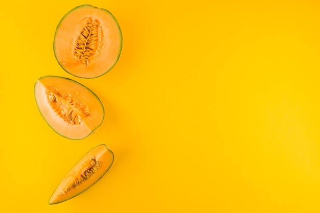 Slices of cantaloupe fruit against yellow backdrop