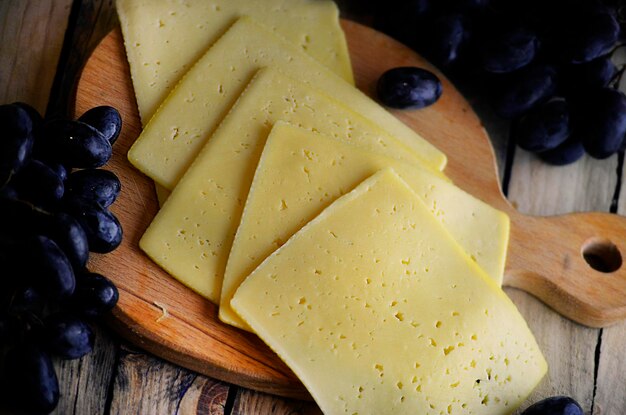 Slices of cheese and a bunch of grapes