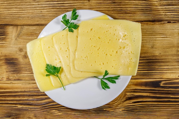 Slices of cheese in a plate on wooden table Top view