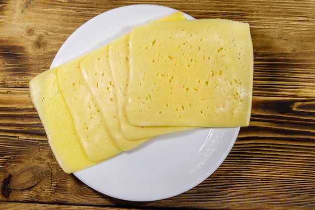 Slices of cheese in a plate on wooden table top view