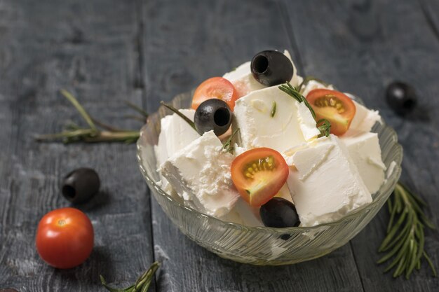 Fette di pomodorini e olive in una ciotola con formaggio feta. insalata con formaggio e verdure.