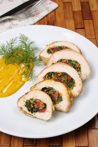 Slices of chicken breast stuffed with spinach, carrot, pepper, tomato on a plate