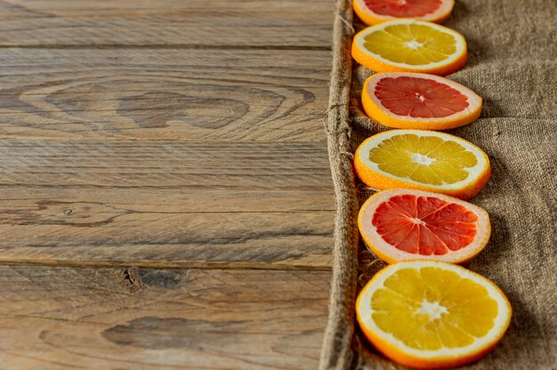柑橘系の果物のスライスを続けて。食品の背景。黄麻布にオレンジとグレープフルーツ。