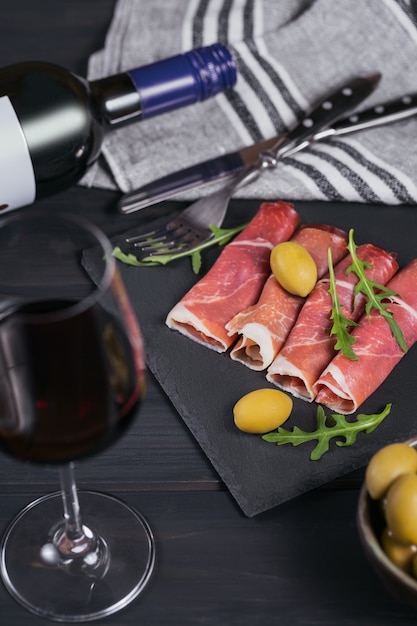 slices of cured ham or spanish jamon serrano or italian prosciutto crudo with glass of red wine