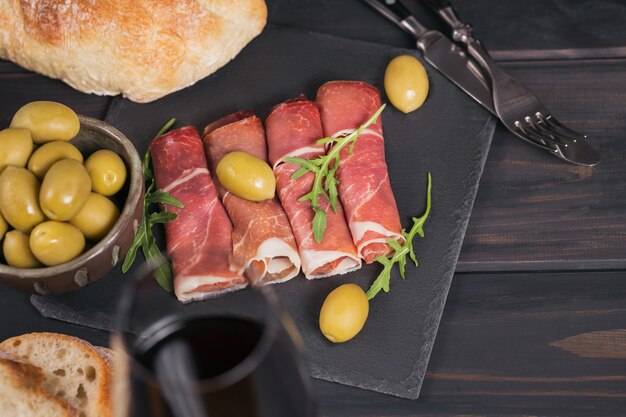 slices of cured ham or spanish jamon serrano or italian prosciutto crudo with glass of red wine