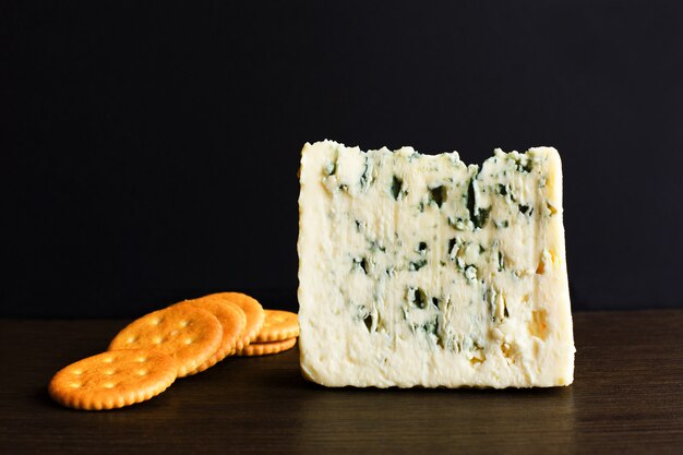 Slices of Danish Blue cheese and cookies on an old wooden table.