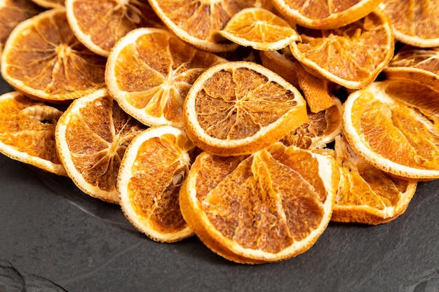 Slices of dehydrated orange on black stone. Selective focus.