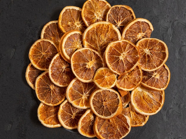 Slices of dehydrated orange on black stone. Selective focus.