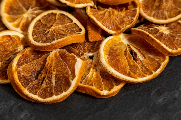 Photo slices of dehydrated orange on black stone. selective focus.