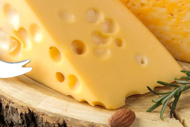 Slices of delicious marbled cheese and Maasdam cheese with honey, rosemary and mendal on a dark background. close-up