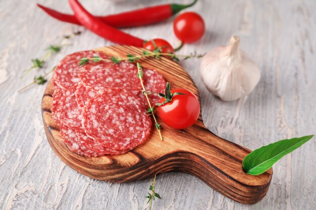 Slices of delicious smoked sausage on wooden board