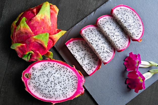 Slices of dragon Fruit with flowers on a stone and wood base Pitaya tropical fruit