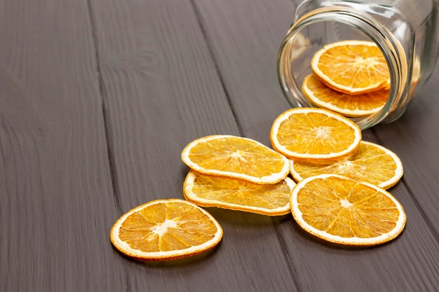 Slices of dried orange are scattered from a glass jar on the table