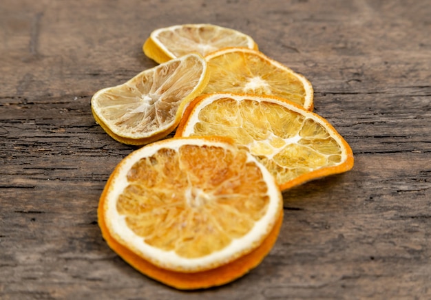 Slices of dried oranges lying in the center of a wooden table. 